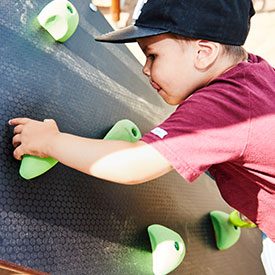 Boy climbing a climbing wall of a multi play structure 